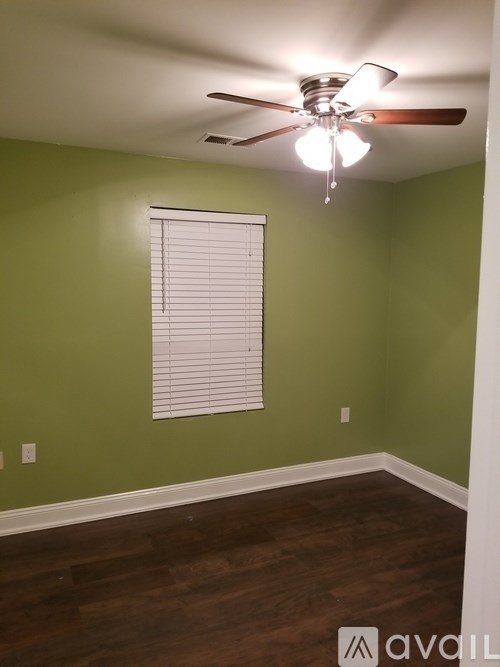 A room with a ceiling fan and a window with blinds.
