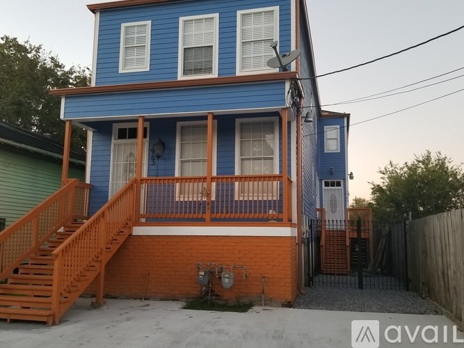 A blue house with a wooden staircase leading to the front door.