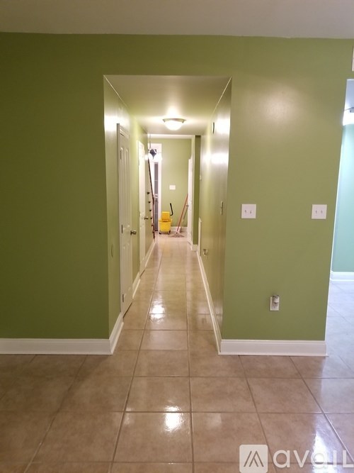 A long hallway with green walls and tile flooring.