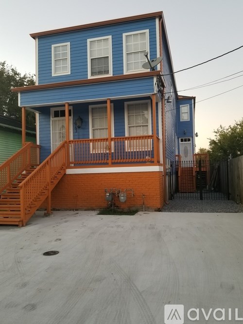A blue house with a wooden staircase leading to the front door.