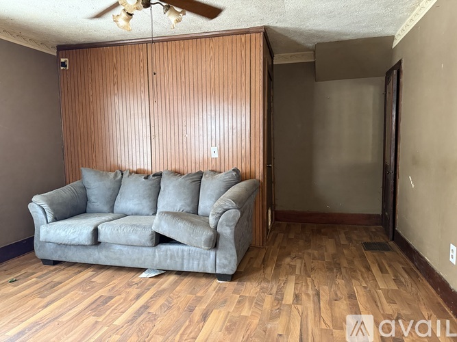 A living room with a grey couch and wooden flooring.