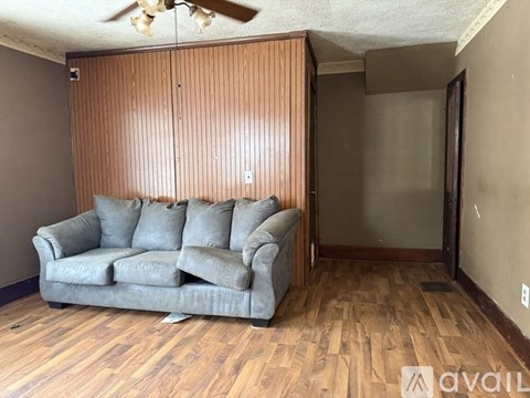 A living room with a grey couch and wooden flooring.