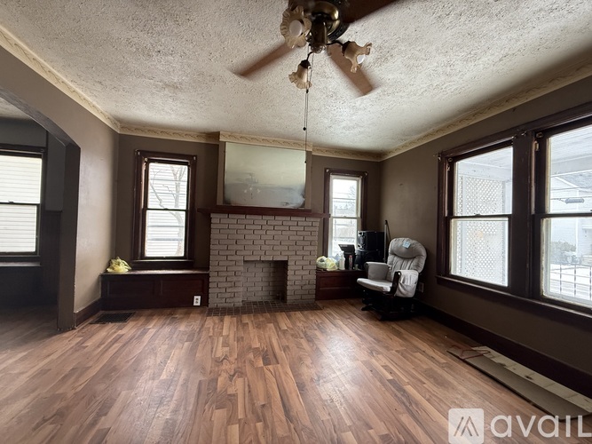 A living room with a fireplace and a ceiling fan.