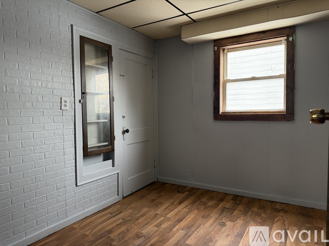A room with a white brick wall and a wooden floor.