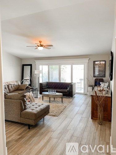 A living room with a brown couch and a fan on the ceiling.