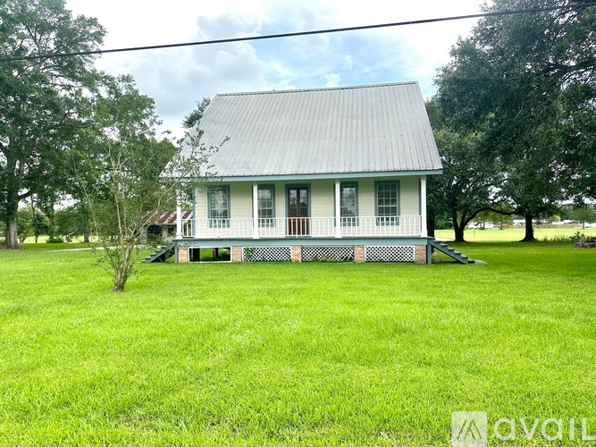 A small house with a porch is surrounded by a grassy field.