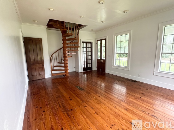 A spacious room with wooden floors and a spiral staircase.