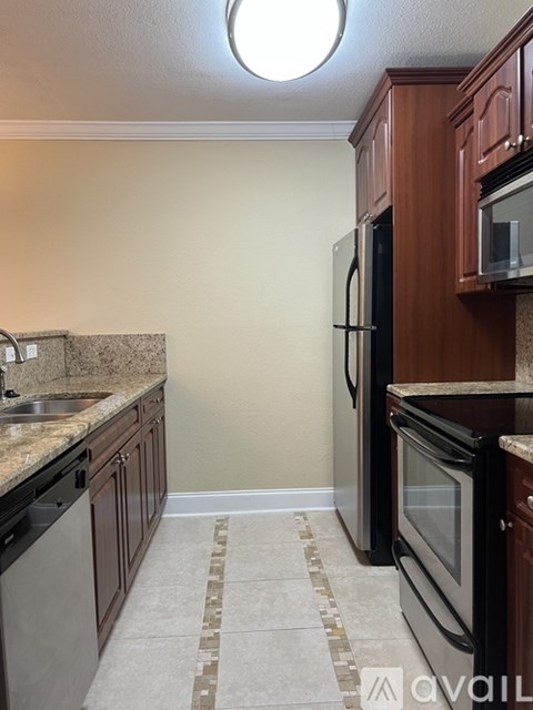 A kitchen with brown cabinets and a black fridge.