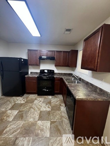 A kitchen with brown cabinets and a black refrigerator.