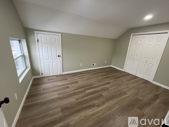 A room with wooden flooring and two white doors.