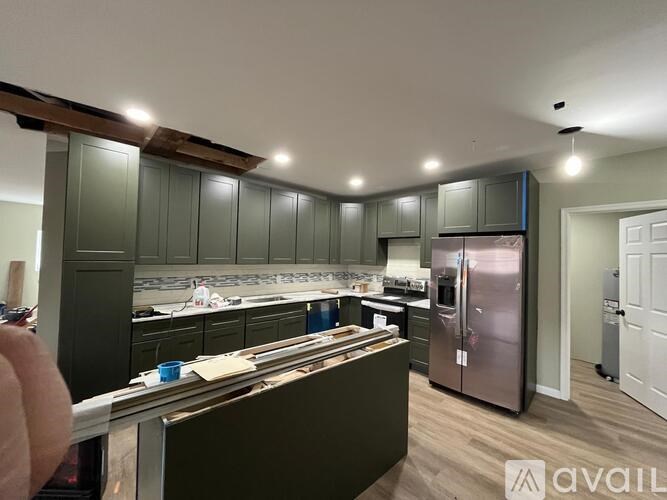A kitchen with green cabinets and a stainless steel refrigerator.