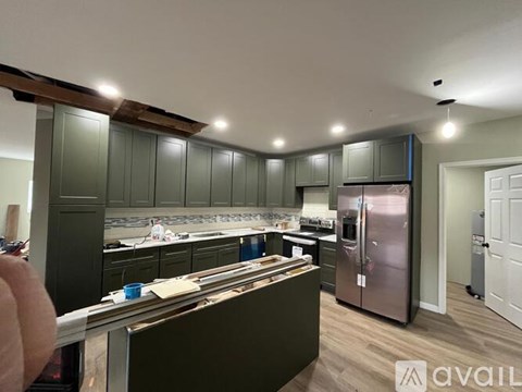A kitchen with green cabinets and a stainless steel refrigerator.