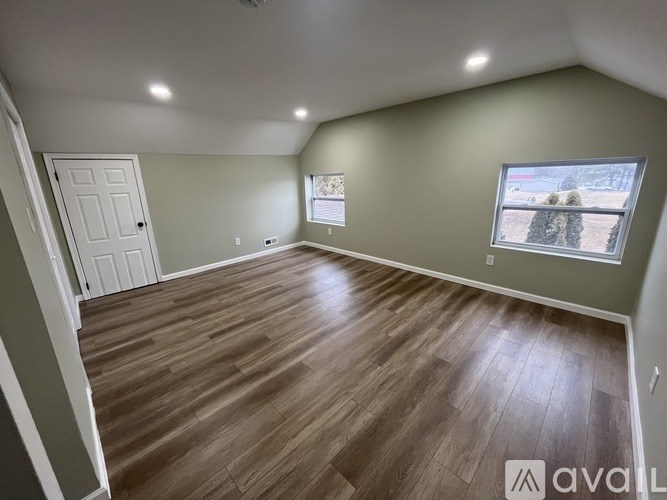 A room with wooden flooring and a window showing a snowy landscape outside.