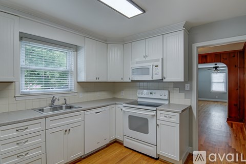 A kitchen with white cabinets and appliances.