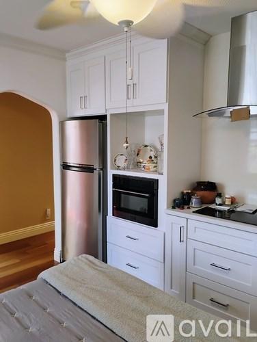 A kitchen with white cabinets and a stainless steel refrigerator.