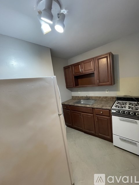 A kitchen with a white refrigerator, brown cabinets, and a white stove top oven.