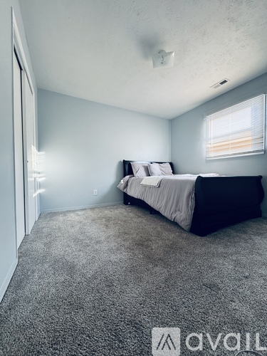 A bedroom with a bed and a carpeted floor.