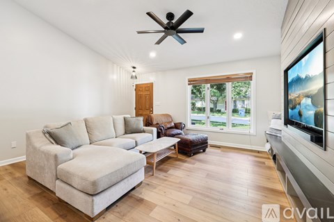 A spacious living room with a large grey sectional sofa and a flat screen TV mounted on the wall.