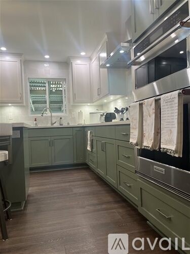 A kitchen with green cabinets and stainless steel appliances.
