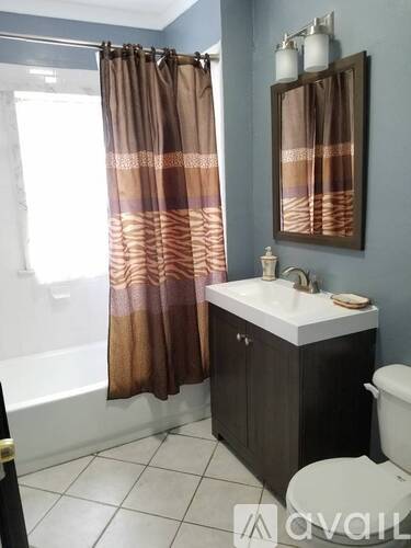 A bathroom with a brown shower curtain and a white sink.