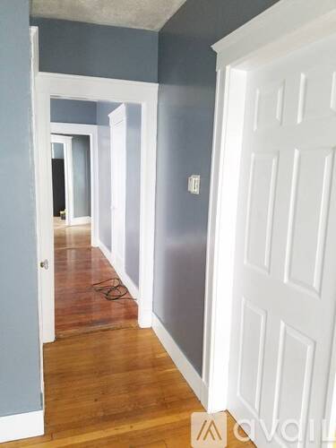 A hallway with white doors and a wooden floor.