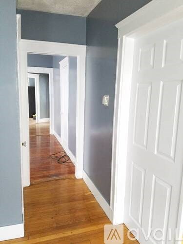 A hallway with white doors and a wooden floor.
