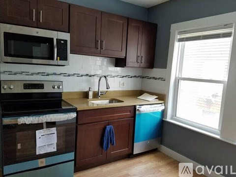 A kitchen with brown cabinets and a blue dishwasher.