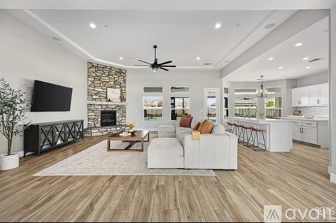 A spacious living room with a white sofa set, a stone fireplace, and a television.