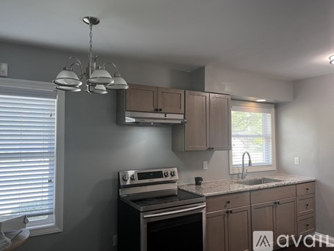 A kitchen with a stove, sink, and cabinets.