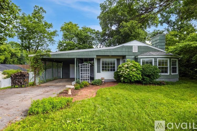 A house with a green lawn and trees in the background.