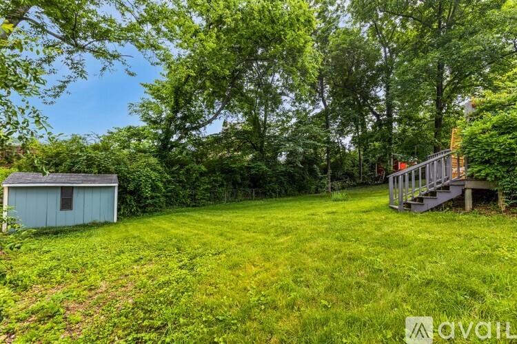 A grassy field with a shed and a deck.