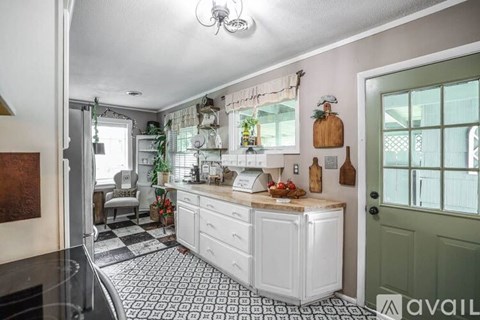 A kitchen with white cabinets and a black and white checkered floor.