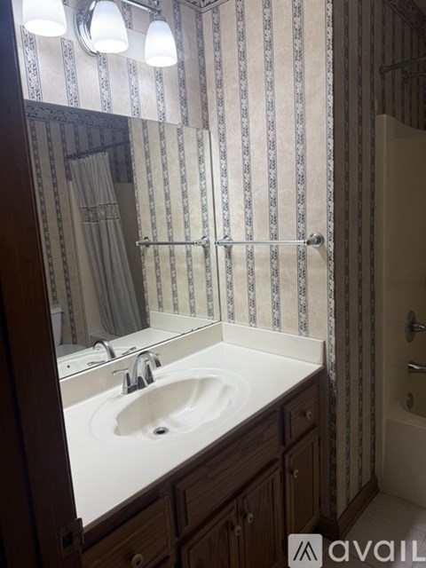 A bathroom with a sink, mirror, and striped wallpaper.