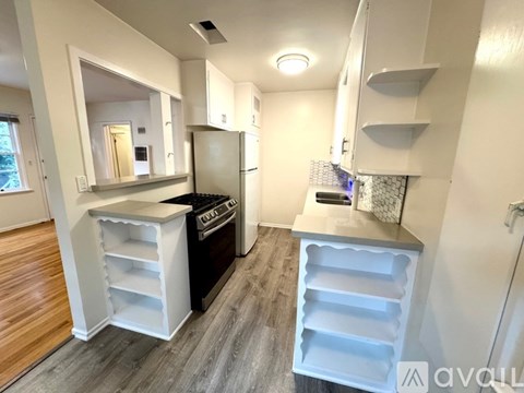A kitchen with white cabinets and a black fridge.