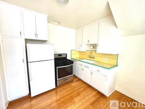 A kitchen with white cabinets and a wooden floor.