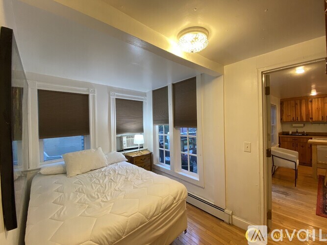 A bedroom with a large bed and a window with blinds.