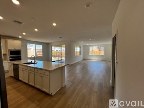 A spacious kitchen with white cabinets and a wooden floor.
