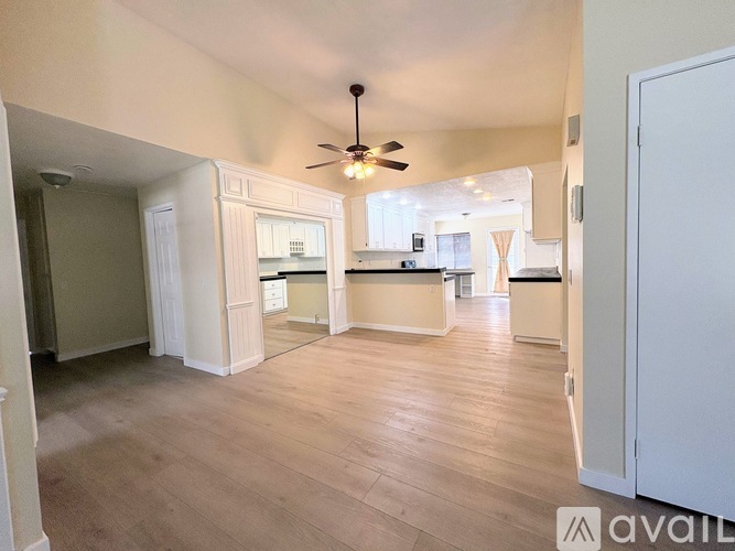 A spacious living room with a ceiling fan and hardwood floors.