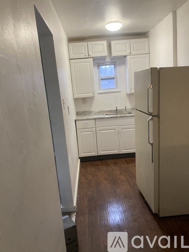 A kitchen with white cabinets and a refrigerator.