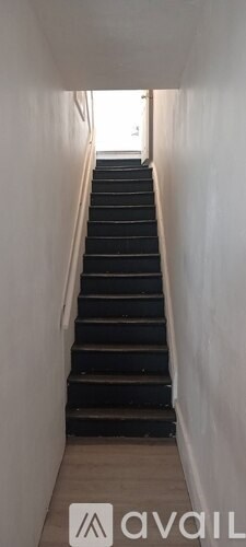 A long staircase with black steps and white walls.