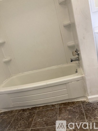 A white bathtub with a shower head and a white door.