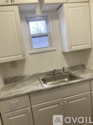 A kitchen with white cabinets and a marble countertop.