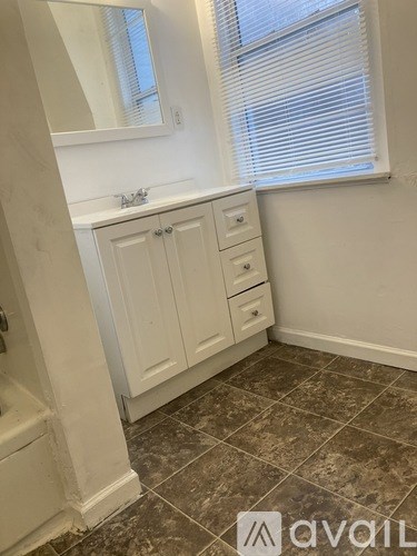 A bathroom with a tiled floor and white walls.