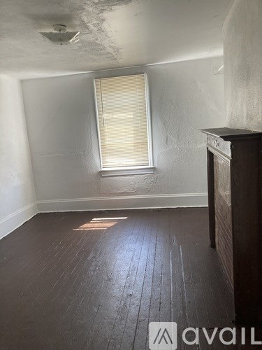 A room with wooden floors and a window with blinds.