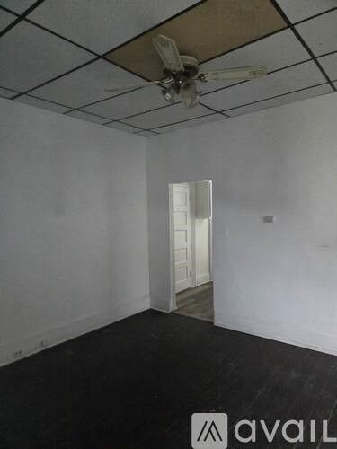 A room with a ceiling fan and a doorway leading to another room.