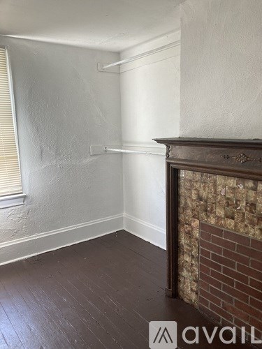 A room with a brick fireplace and wooden floors.