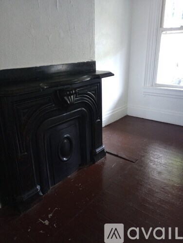 A black fireplace in a room with wooden floors.