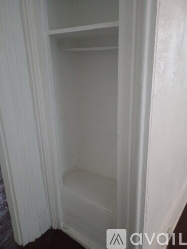 A white closet with a shelf and a white curtain.