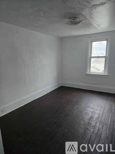 A room with a window and wooden floors.