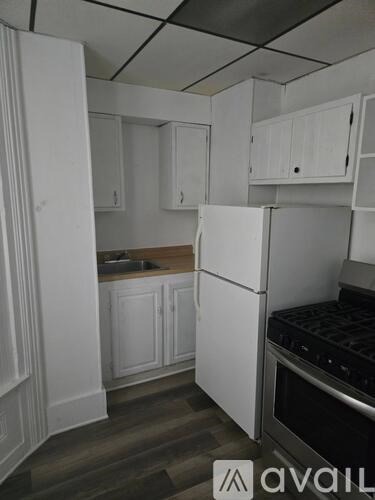 A kitchen with white cabinets and a white refrigerator.